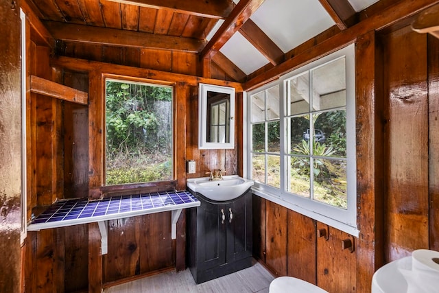 unfurnished sunroom with vaulted ceiling with beams, plenty of natural light, and sink