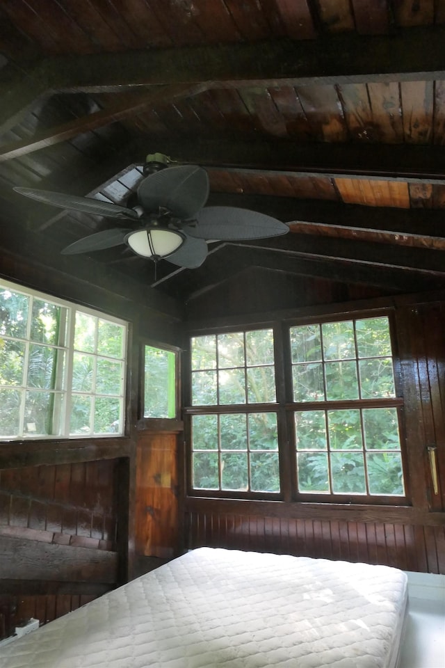 unfurnished bedroom featuring lofted ceiling with beams, wood walls, wooden ceiling, and multiple windows