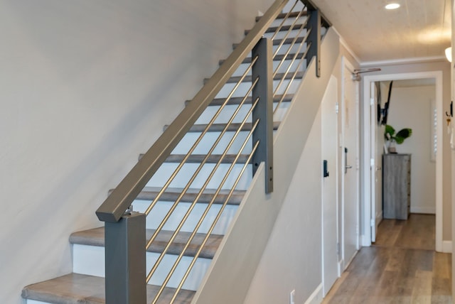 stairway featuring baseboards, wood finished floors, recessed lighting, and a water view