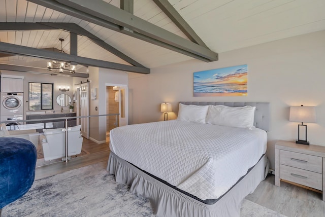 bedroom featuring lofted ceiling with beams, wood finished floors, stacked washing maching and dryer, and a chandelier