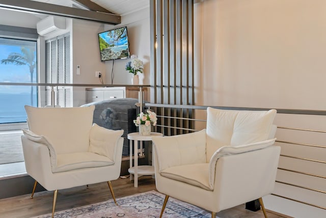 living area featuring lofted ceiling with beams, wood finished floors, and a wall unit AC
