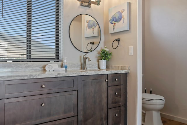 bathroom featuring baseboards, toilet, and vanity