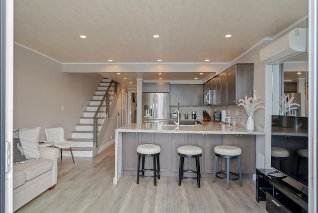 kitchen with light countertops, an AC wall unit, a sink, a peninsula, and appliances with stainless steel finishes