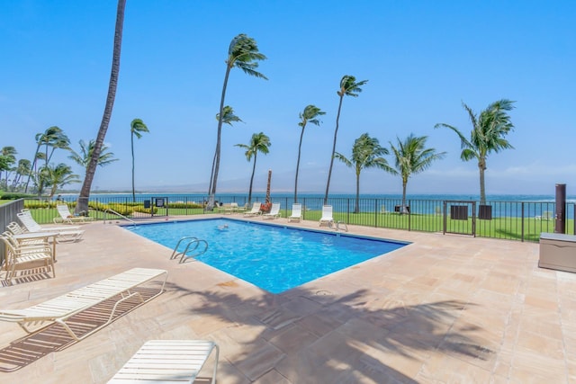 pool featuring a patio area, a water view, and fence
