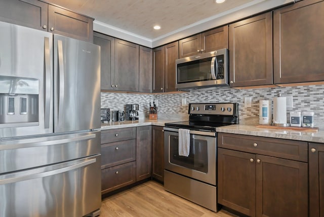 kitchen with light wood finished floors, tasteful backsplash, appliances with stainless steel finishes, and dark brown cabinetry