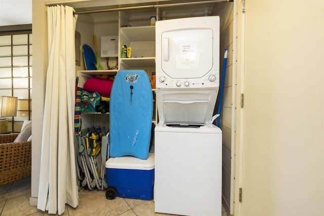 clothes washing area featuring stacked washer / drying machine and light tile patterned flooring