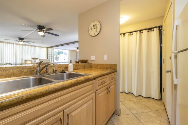 kitchen with ceiling fan, white refrigerator, light brown cabinetry, sink, and light tile patterned flooring