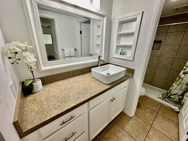 bathroom with toilet, walk in shower, tile patterned flooring, and vanity