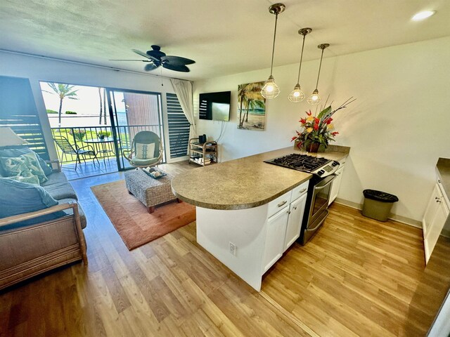 kitchen with white cabinets, light wood-type flooring, stainless steel range with gas stovetop, and ceiling fan