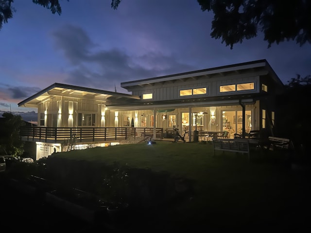 back house at dusk featuring a lawn