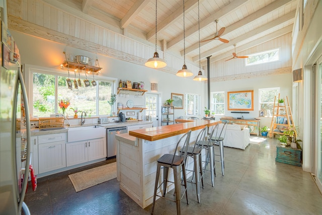 kitchen with a kitchen island, ceiling fan, white cabinets, a kitchen bar, and dishwasher