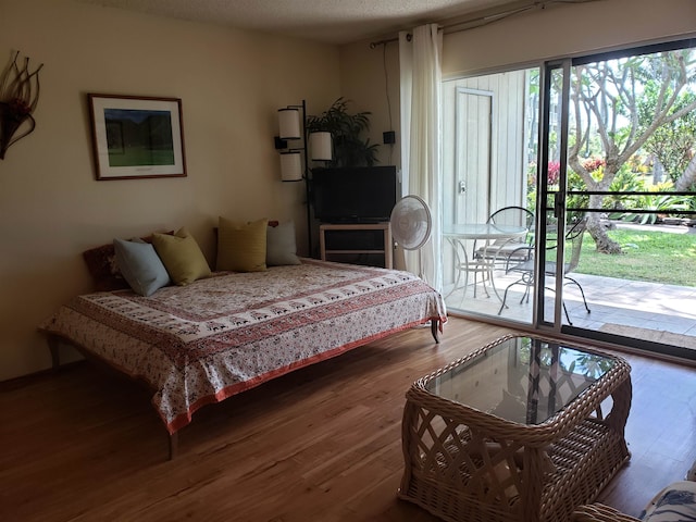 bedroom with a textured ceiling, access to exterior, and hardwood / wood-style flooring