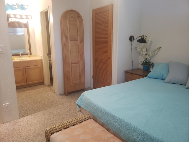 bedroom featuring light carpet, ensuite bath, a closet, and sink