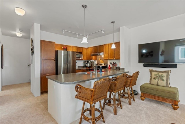 kitchen with pendant lighting, stainless steel appliances, sink, a kitchen breakfast bar, and kitchen peninsula