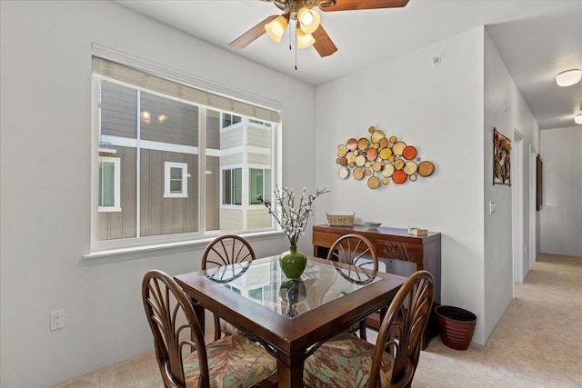 dining space with ceiling fan and light carpet