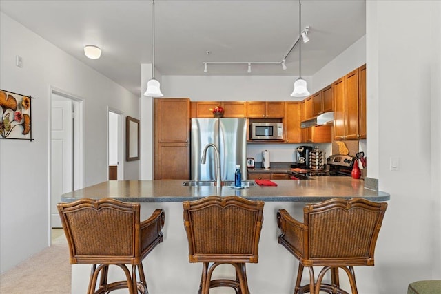 kitchen with hanging light fixtures, kitchen peninsula, appliances with stainless steel finishes, and a kitchen bar