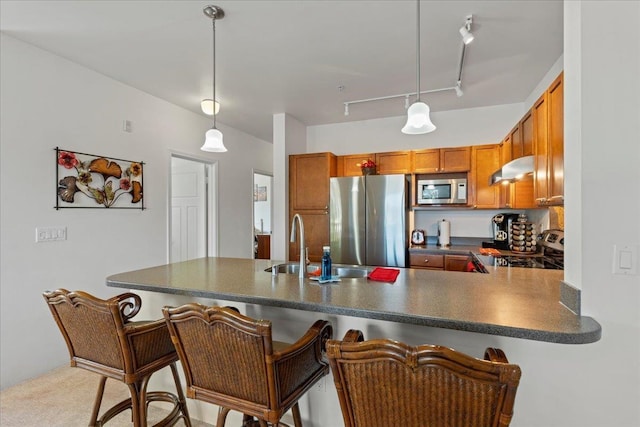 kitchen with rail lighting, hanging light fixtures, appliances with stainless steel finishes, and kitchen peninsula