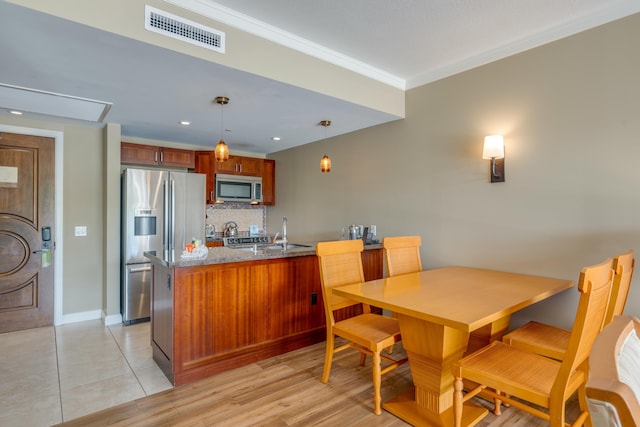 kitchen with crown molding, tasteful backsplash, stainless steel appliances, stone counters, and decorative light fixtures