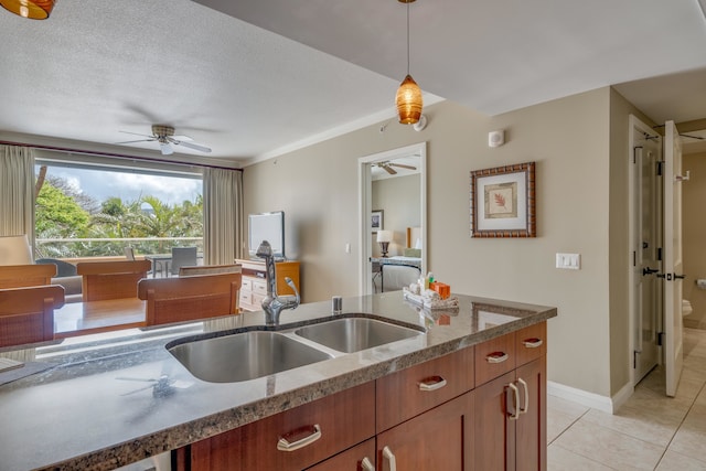 kitchen featuring ceiling fan, light tile flooring, decorative light fixtures, a textured ceiling, and sink