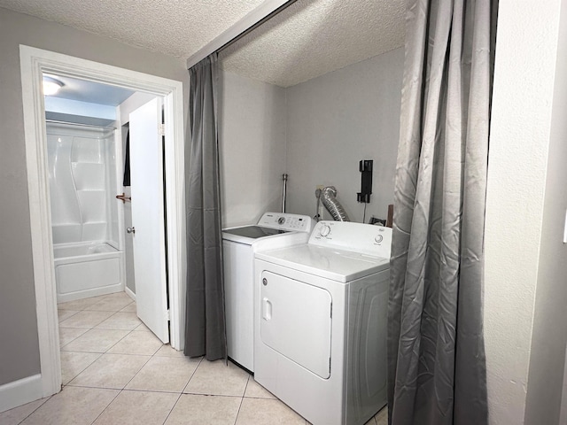 laundry room featuring light tile patterned floors, a textured ceiling, and washing machine and clothes dryer