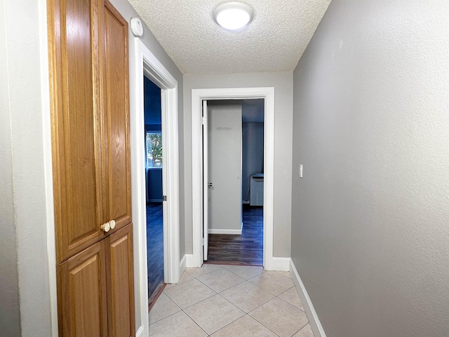 corridor with light tile patterned floors and a textured ceiling