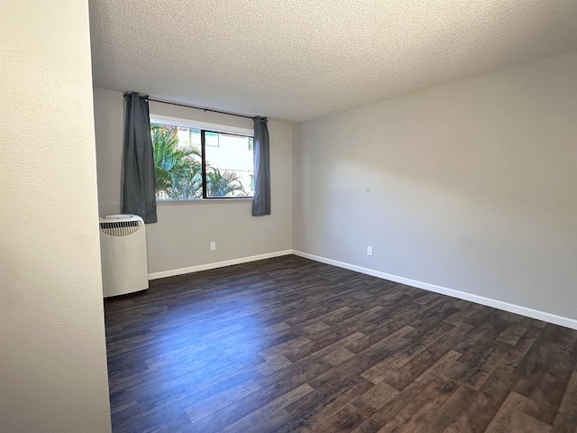 empty room with dark hardwood / wood-style flooring and a textured ceiling