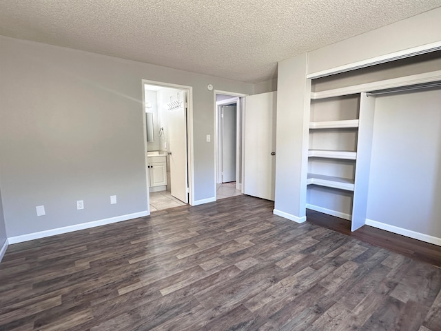 unfurnished bedroom with a textured ceiling, dark hardwood / wood-style flooring, ensuite bathroom, and a closet