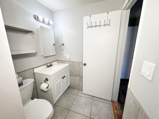 bathroom featuring tile patterned flooring, vanity, toilet, and tile walls