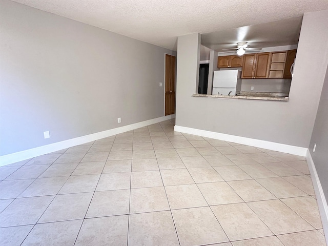 unfurnished living room featuring ceiling fan, light tile patterned flooring, and a textured ceiling