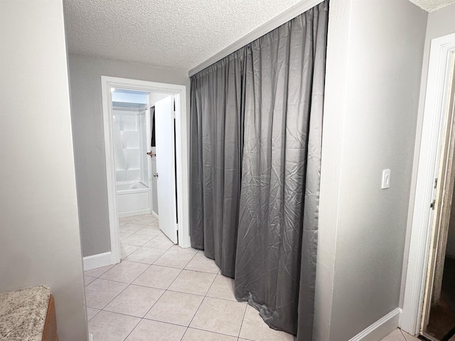 hallway with light tile patterned floors and a textured ceiling