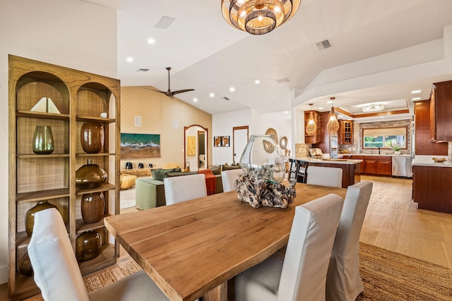 dining space featuring ceiling fan with notable chandelier, vaulted ceiling, and light hardwood / wood-style flooring