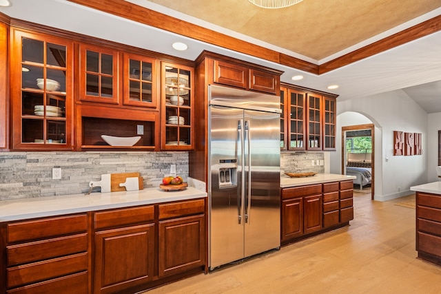 kitchen featuring decorative backsplash, light hardwood / wood-style floors, stainless steel built in refrigerator, and vaulted ceiling