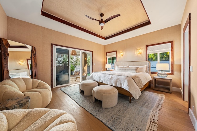 bedroom featuring ceiling fan, multiple windows, access to outside, and light hardwood / wood-style flooring