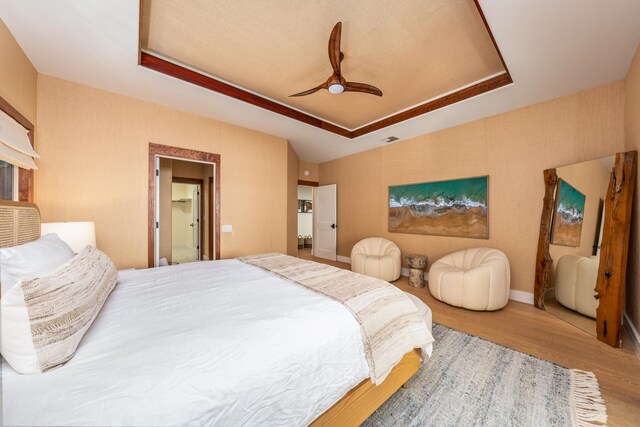 bedroom with a tray ceiling, ceiling fan, and hardwood / wood-style floors