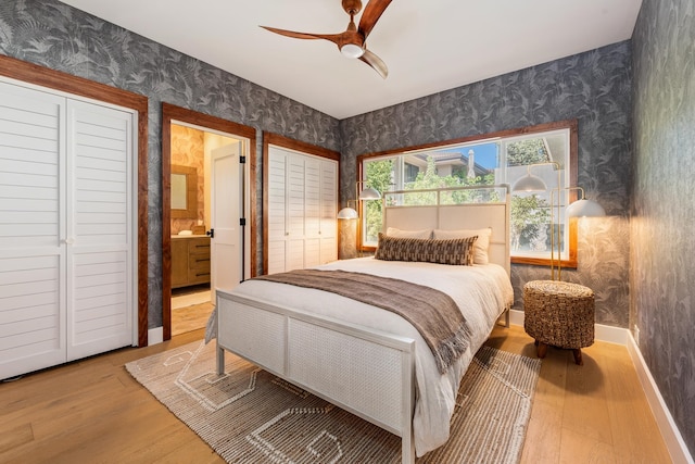 bedroom with ceiling fan, two closets, light wood-type flooring, and ensuite bath