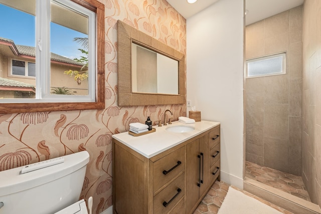 bathroom featuring vanity, a healthy amount of sunlight, toilet, and tiled shower