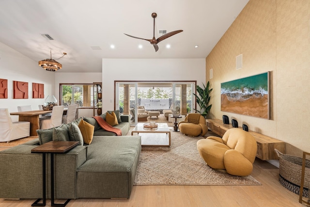 living room with ceiling fan with notable chandelier and light hardwood / wood-style floors