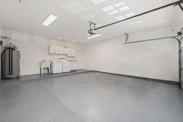 garage featuring electric water heater, washer and clothes dryer, a garage door opener, and sink