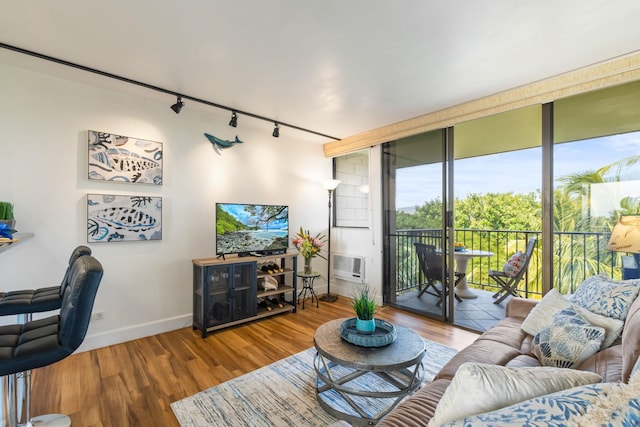 living area with baseboards, wood finished floors, rail lighting, an AC wall unit, and floor to ceiling windows