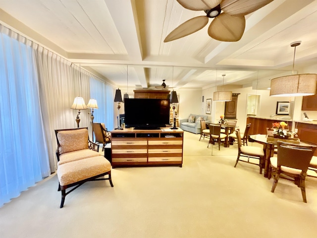 sitting room with beamed ceiling, ceiling fan, and light carpet