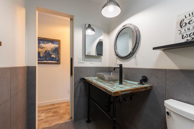 bathroom featuring hardwood / wood-style flooring, vanity, toilet, and tile walls