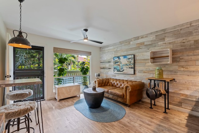 living room with ceiling fan, wood walls, and light hardwood / wood-style flooring