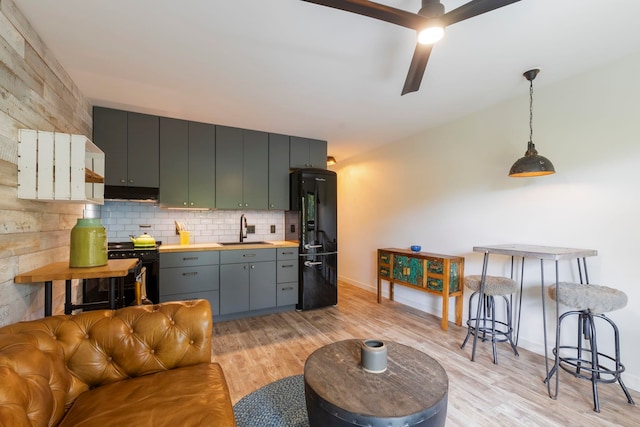 kitchen with sink, black appliances, decorative light fixtures, light hardwood / wood-style flooring, and butcher block counters