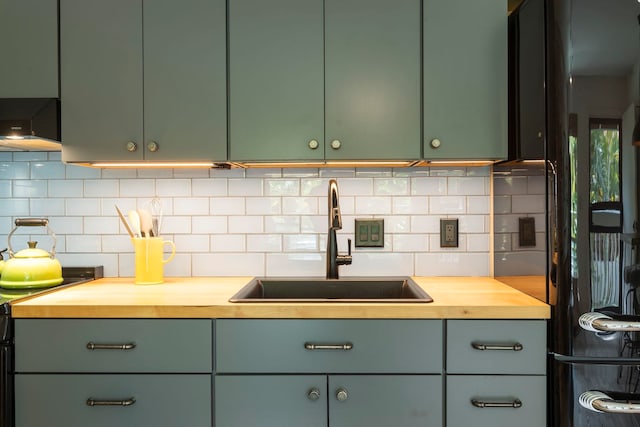 kitchen featuring stove, butcher block counters, sink, and tasteful backsplash