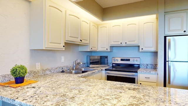 kitchen with white cabinets, light stone counters, sink, and appliances with stainless steel finishes