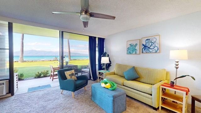 carpeted living room featuring a textured ceiling, a water view, and ceiling fan