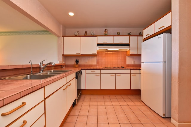 kitchen with decorative backsplash, white cabinets, white appliances, tile counters, and sink