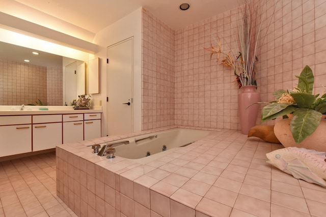 bathroom with vanity, a relaxing tiled tub, tile walls, and tile patterned flooring