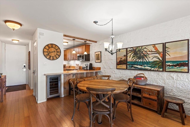 dining space featuring dark hardwood / wood-style floors, beverage cooler, and a chandelier