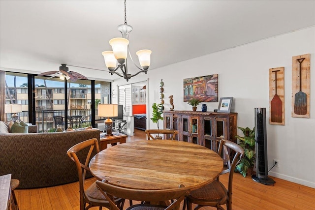 dining space with ceiling fan with notable chandelier and light hardwood / wood-style floors